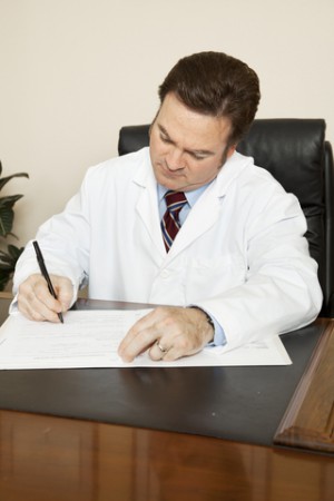 doctor sat at desk writing notes