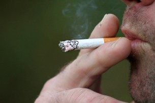 male hand and mouth smoking a cigarette